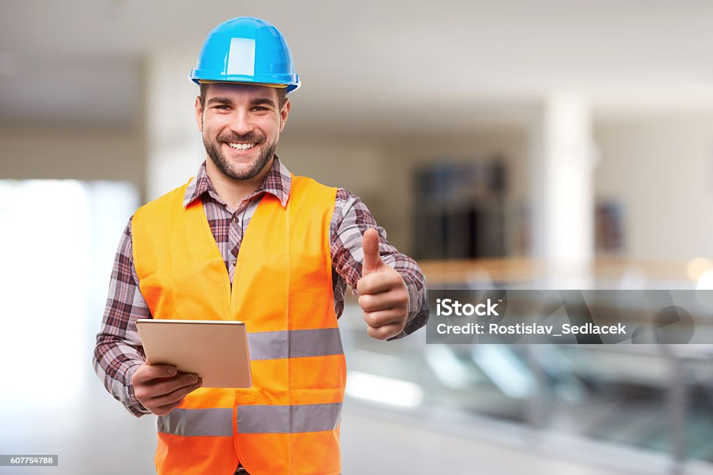 Trabajador manual sonriente en el gesto del casco azul pulgar hacia arriba - Foto de stock de Seguridad libre de derechos