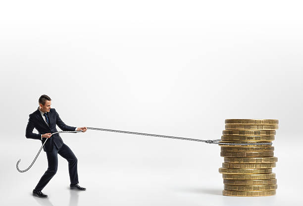 istock Businessman pulling stack of big golden coins with a rope 607757150