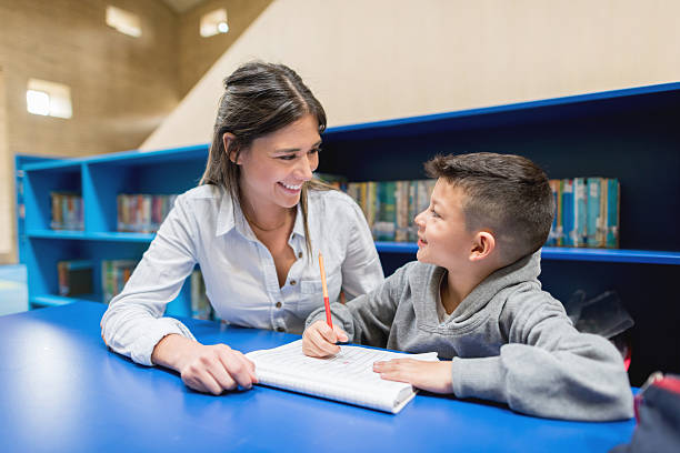 profesor con un alumno en la biblioteca - maestro particular fotografías e imágenes de stock