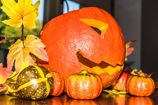 istock Jack O'Lantern cutout from a small pumpkin on wooden table 607759632