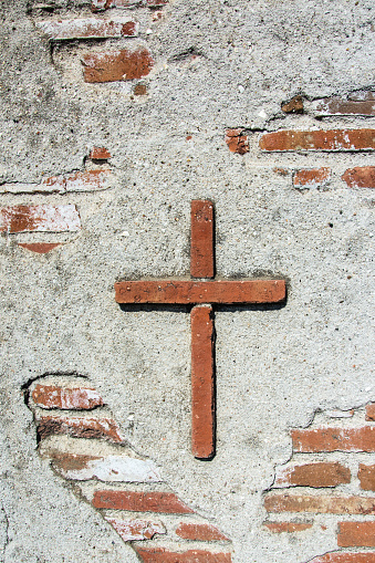 Stone cross in an old adobe wall around the mission