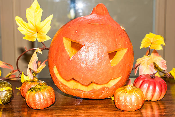 istock Jack O'Lantern cutout from a small pumpkin on wooden table 607761362