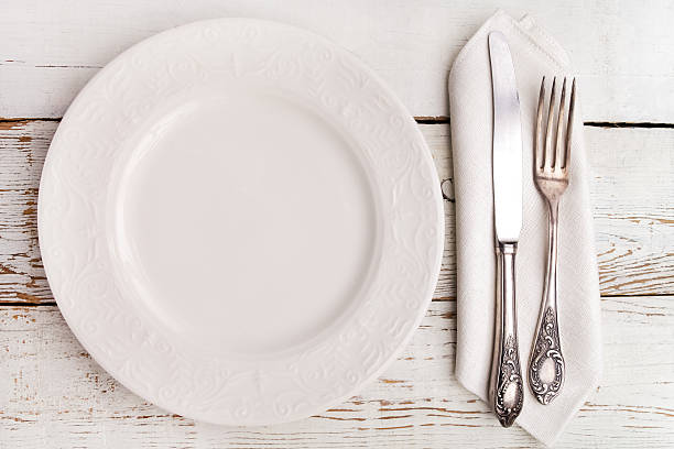 istock Plate, fork and knife on white wooden table 607763050