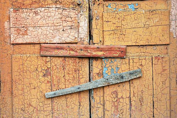 Abandoned broken wooden shed door and lock. scored plank window