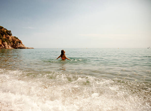 Girl alone in shallow waters, at a beach.