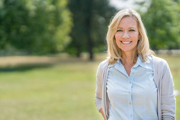 Portrait of a happy woman at the park Portrait of a happy adult woman at the park looking at the camera smiling - older blonde woman stock pictures, royalty-free photos & images