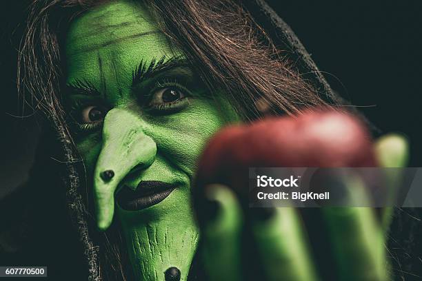 Böse Hexe Schaut Auf Kamera Hält Einen Roten Apfel Stockfoto und mehr Bilder von Hexe - Hexe, Halloween, Apfel