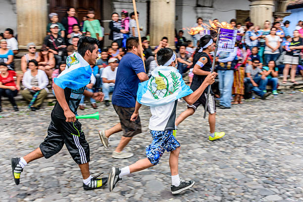 Runners with torches, Independence Day, Antigua, Guatemala Antigua, Guatemala - September 14, 2015: Locals run in streets with lit torches & flags draped around them & blow whistles during Guatemalan Independence Day celebrations puerto quetzal guatemala stock pictures, royalty-free photos & images