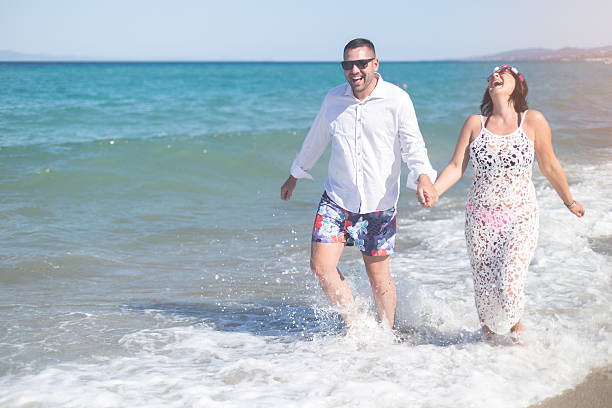 istock Couple holding hands and walking on a beach 607775532