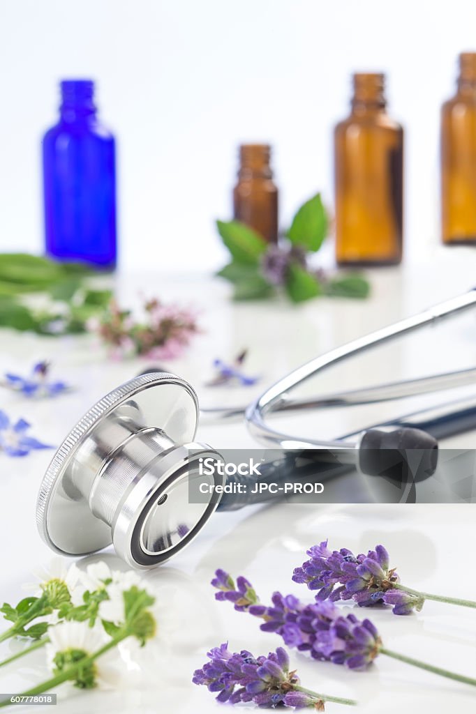 Bottle of essential oil with medicinal plant and stethoscope Bottle of essential oil with medicinal plant and stethoscope on white Alternative Therapy Stock Photo