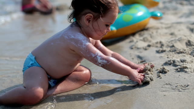 baby playing in the sea on the beach sand