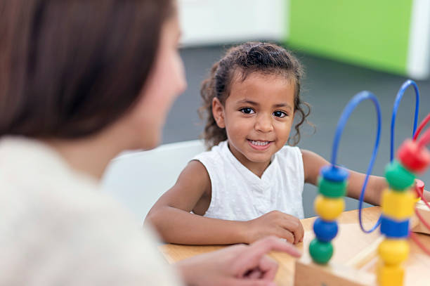 une jeune fille souriant pendant sa séance de thérapie - child therapy photos et images de collection