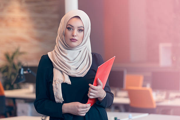 istock Arabian business woman holding a folder in modern startup office 607873154