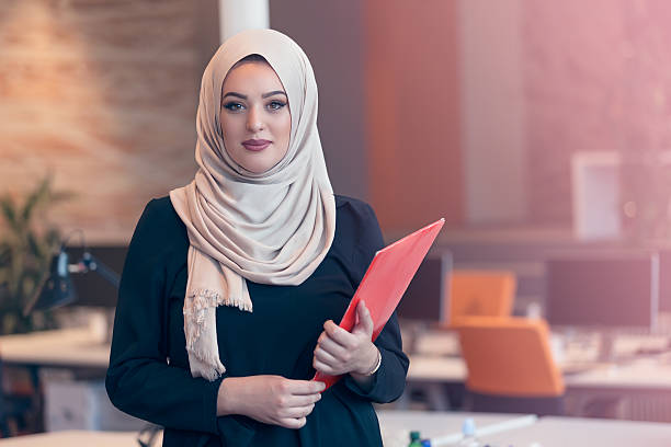 istock Arabian business woman holding a folder in modern startup office 607873532