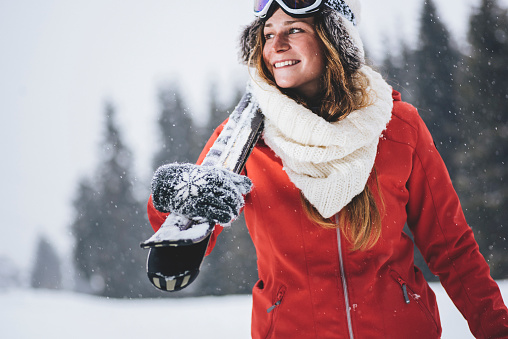 Young happy woman carrying skis trough snow