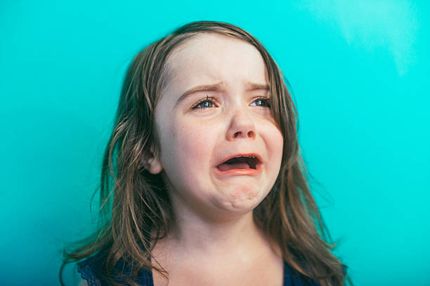 This is a horizontal, color photograph of an adorable four year old, little girl screaming and crying as she has a temper tantrum. Photographed with a Nikon D800 DSLR camera.