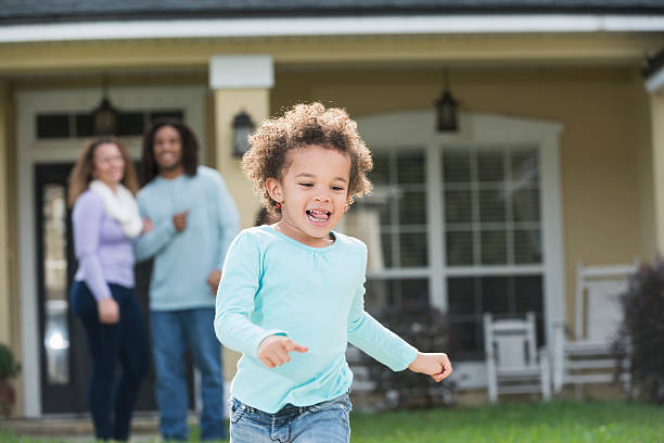 istock Proud parents watch young daughter run in front yard 607881638
