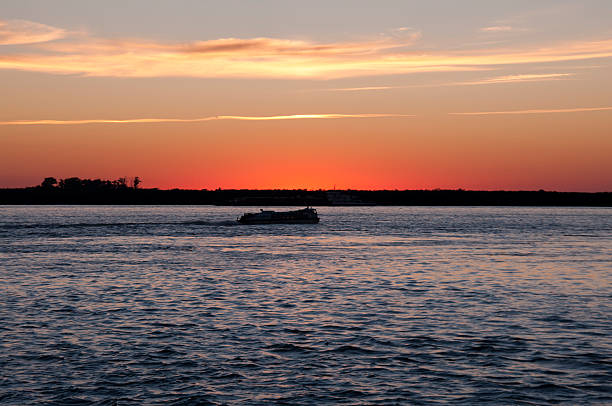 istock Boat sails along  Amur river on sunset sky background  607886810