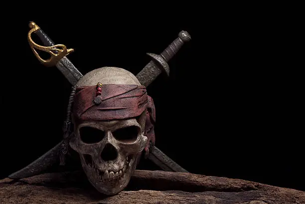 pirate skull with two swords over darkness background still life style