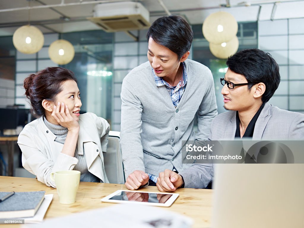 young asian entrepreneurs discussing business in office a team of young asian entrepreneurs having a discussion in office. Business Stock Photo