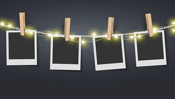 Blank photo frame hanging on rope with fairy lights Vector EPS 10 format. black border photos stock illustrations