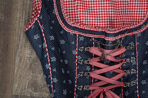 A beautiful blue and red checked dirndl on a rustic old hardwood table. A dirndl is a traditional female dress in the Austrian and German Bavarian culture. Very beautiful details. No people are visible. Photo made indoor in a professional photo studio.