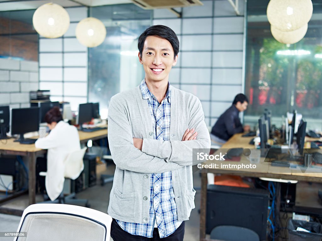 portrait of a young asian entrepreneur confident young asian entrepreneur standing in own company looking at camera arms crossed smiling. 20-29 Years Stock Photo