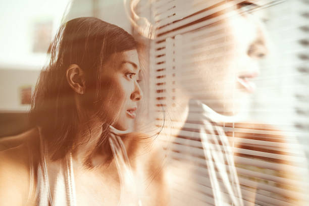 istock asian woman looking outside the window 607901632