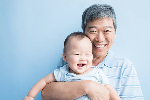 grandfather hold grandson happily grandfather hold grandson happily with isolated blue background, asian china chinese ethnicity smiling grandparent stock pictures, royalty-free photos & images