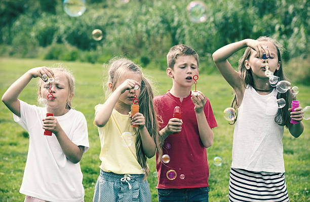 istock children blowing bubbles in park 607911628