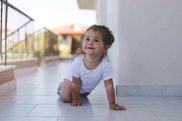 portrait of a baby girl on a terrace hallway - baby tile crawling tiled floor imagens e fotografias de stock