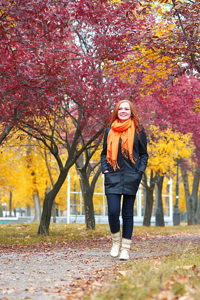 istock girl walk on pathway in city park with red trees 607916196