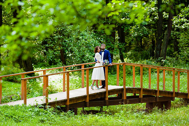 istock Bride and groom walking on a wooden bridge 607916410