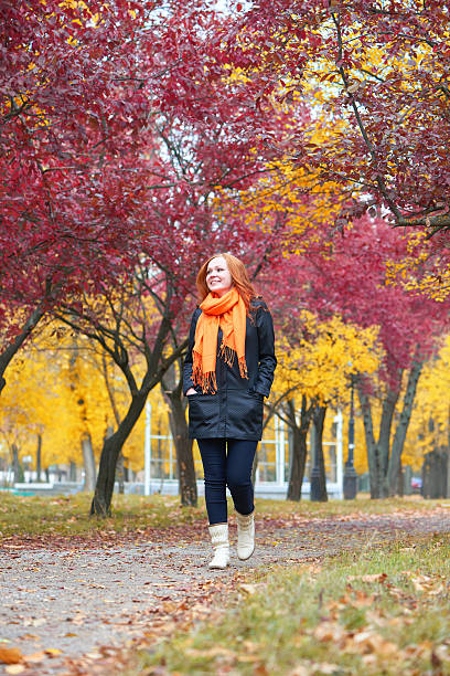 istock girl walk on pathway in city park with red trees 607917210