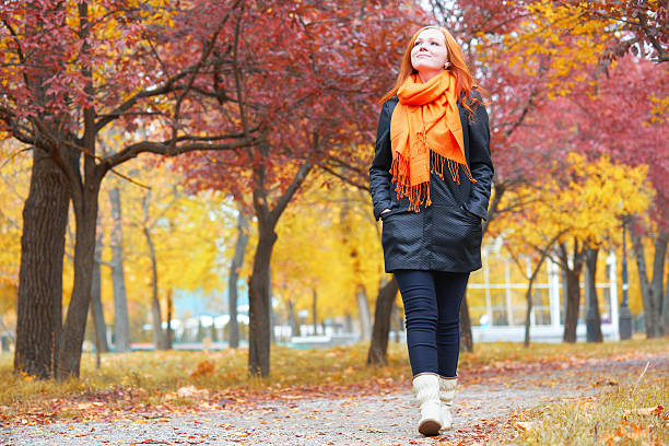 istock girl walk on pathway in city park with red trees 607918262