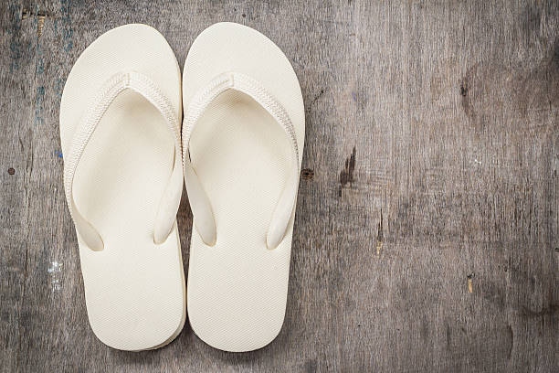 istock Flip-flops cream color on a wooden background. 607920124