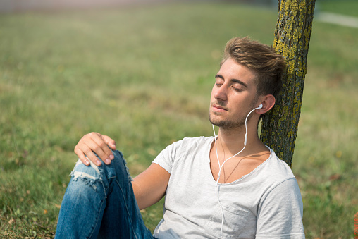 Young man listening to the music in the park