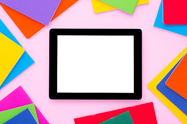 istock Blank tablet with colorful notebooks around on bright pink background. 607924306