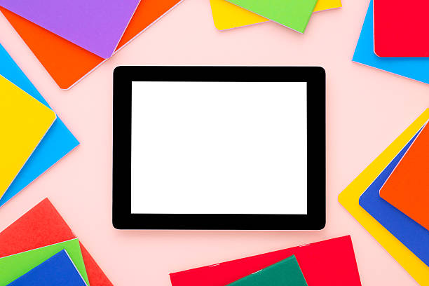istock Blank tablet with colorful notebooks around on bright pink background. 607924334