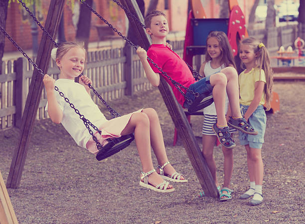istock Happy friends swinging on swing 607924898