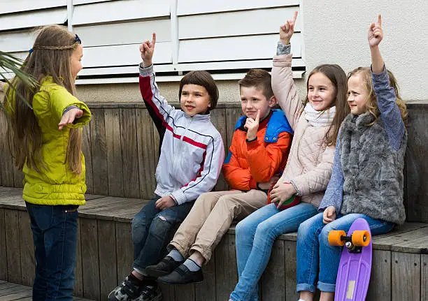 Positive kids trying to guess what friend shows in charades in town