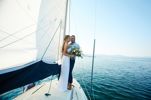 Happy married couple traveling by yacht during honeymoon