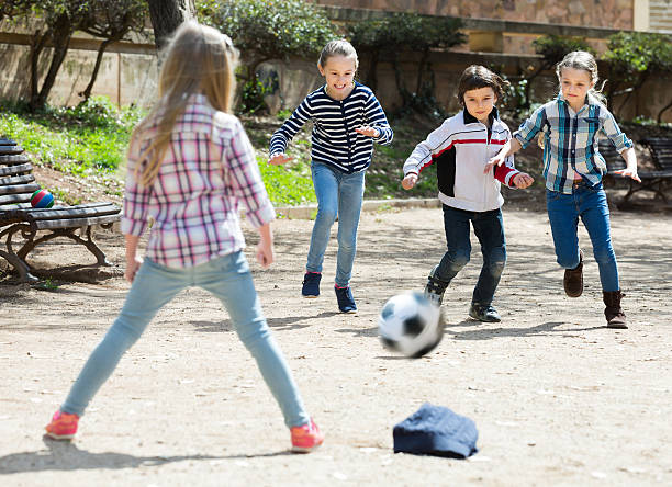 bambini piccoli che giocano a calcio di strada all'aperto - football player group of people running american football foto e immagini stock