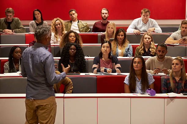 Back view of man presenting to students at a lecture Back view of man presenting to students at a lecture theatre classrooms stock pictures, royalty-free photos & images