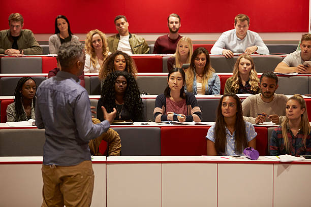 Back view of man presenting to students at a lecture Back view of man presenting to students at a lecture theatre lecturer stock pictures, royalty-free photos & images