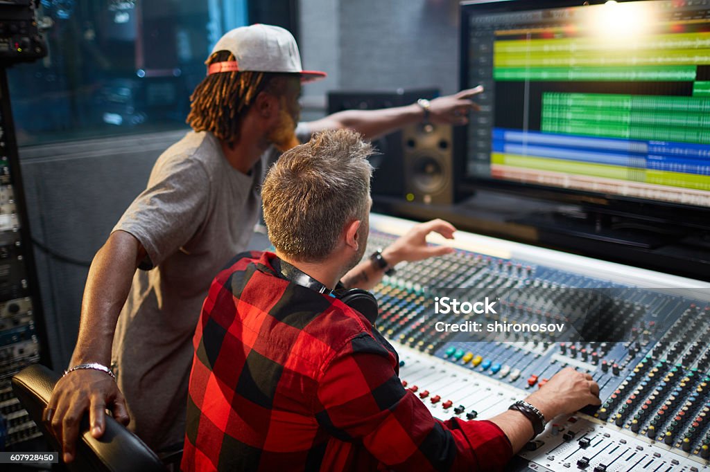 Mixing sounds Sound recorders looking at display showing level of noise Producer Stock Photo