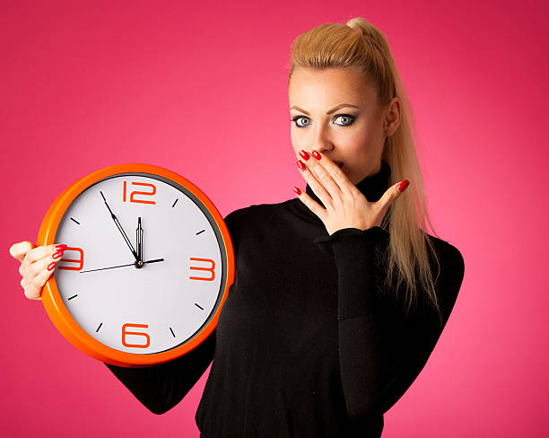 istock Worried woman with big orange clock gesturing delay, rush, nervo 607929096