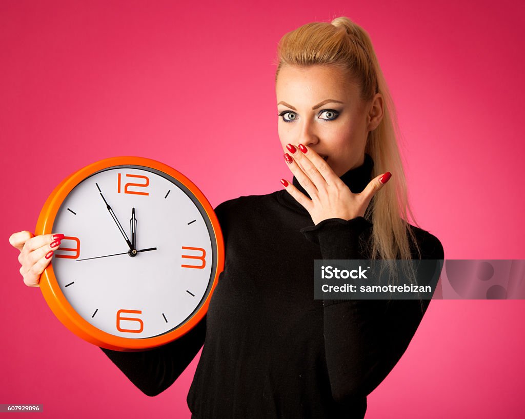Worried woman with big orange clock gesturing delay, rush, nervo Worried woman with big orange clock gesturing delay, rush, nervous, stress because of lack of time. Clock Stock Photo