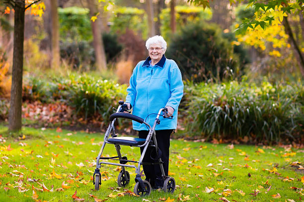 istock Senior lady enjoying walk with walker in autumn park 607929250