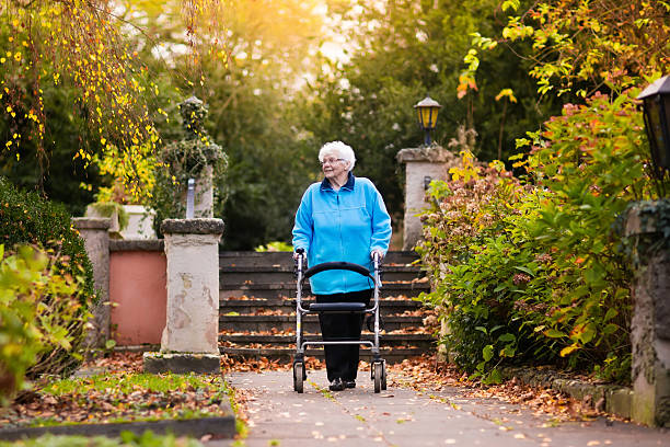 istock Senior lady enjoying walk with walker in sunny autumn park 607959514